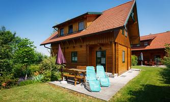 A charming wooden house with a well-maintained garden. There are deck chairs and a sunshade on the terrace to enjoy the sun.