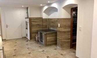 A modern kitchen with bright tiles and wooden paneling. The room is well lit and has an open atmosphere.