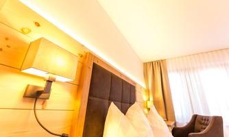 A cozy hotel room with a wooden headboard and soft pillows. The warm lights create an inviting atmosphere.