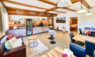 A modern living room with an open kitchen. There are cozy seating options and a stylish decoration.