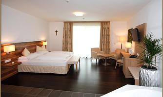 A modern hotel room with a double bed and a cozy seating area. Large windows provide plenty of natural light and a view of the surroundings.