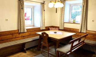A cozy dining area with a wooden table and benches. Large windows let in plenty of light and create an inviting atmosphere.