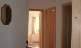 A bright hallway with wood details and a carpet. In the background, open doors to other rooms are visible.