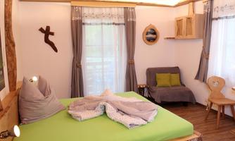 A cozy bedroom with a large bed and fresh, green bed sheets. The room is bright and inviting, with modern furniture and large windows.