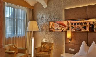 A stylish hotel room with bright walls and cozy furniture. The room has large windows that provide plenty of light.