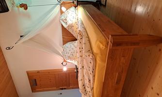 A cozy bedroom with a wooden bed and yellow bedding. Next to the bed are nightstands with lamps and a bright room.