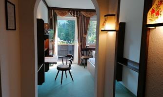 An inviting room with a table and chair, accessed through an arched doorway. Large windows offer a view of the outside and let in plenty of light.