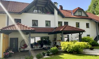 A beautiful house with a red roof and an inviting garden. The outdoor area is well-maintained and surrounded by green plants.