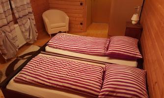 A cozy bedroom with two beds and striped bed covers. The room is clad in wood and has a modern, tranquil style.
