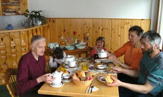 A family gathering at the table with various foods and drinks. The people are enjoying breakfast together in a cozy room.