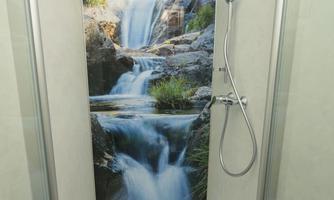 A modern shower with a photorealistic wall mural of a waterfall. The shower setup conveys a sense of freshness and relaxation.