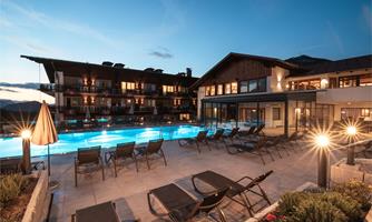 An elegant hotel with a beautiful outdoor pool. It is dusk, and the lights create a cozy atmosphere.