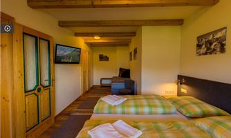 A cozy room with two beds and a TV corner. Wooden decorations and a large window create an inviting atmosphere.
