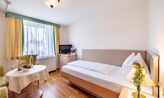 A modern room with a single bed and bright curtains. A table with chairs and a television create a cozy atmosphere.