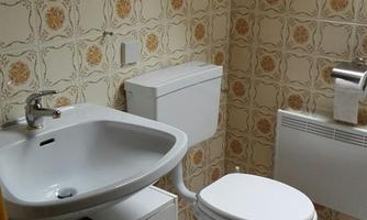 A small bathroom with a white toilet and a sink. The walls are decorated with a floral pattern, and there is a small towel rack.