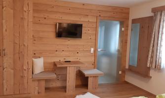A cozy room with wooden-paneled walls. There is a television, a small table, and a glass sliding door.