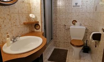 A functional bathroom with a shower, toilet, and sink. The walls are tiled, and there are some bathroom accessories.
