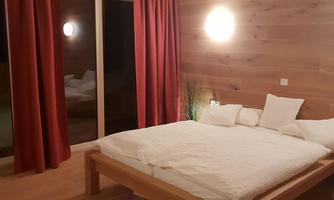 A modern bedroom with a large bed and white pillows. Red curtains and wood-paneled walls create a cozy atmosphere.