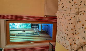 A cozy room with a bed and a view of a balcony. The door to the balcony is open and there is a chair outside.