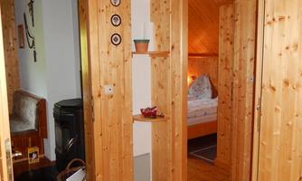 An inviting hallway with wood paneling that leads to a bedroom. On the left side, there is a seating area and decorations.