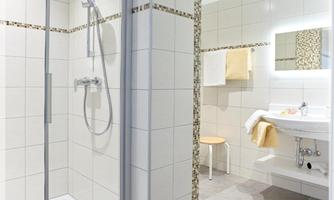 A modern bathroom with a shower area and sink. Well-maintained tiles and bright colors create a pleasant atmosphere.