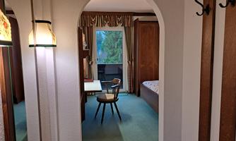A quiet room with a desk and a chair. In the background, there is a window overlooking a garden.