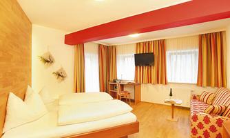 A cozy hotel room with a double bed and a television. The colorful curtains and modern furnishings create an inviting atmosphere.