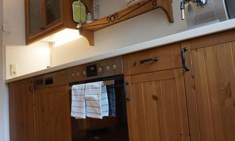 A cozy kitchen with wooden cabinets and modern appliances. A beautiful carpet with a floral pattern lies on the floor.