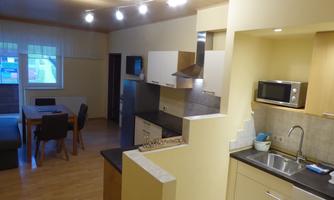 A modern kitchen with a dining area and a cozy living room. The space is bright and friendly designed.