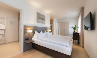 A modern hotel room with two beds and a bright, friendly atmosphere. The room features a minimalist design and a cozy decor.