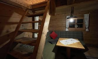 A cozy wooden cabin with a staircase and a table. The light creates an inviting atmosphere.