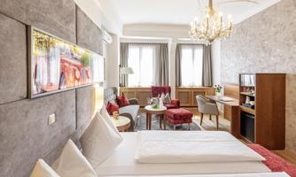 An elegant hotel room with two beds and stylish furniture. Large windows ensure plenty of light and a cozy atmosphere.
