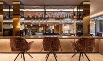 A stylish bar with elegant chairs and a well-stocked drinks wall. The space has a modern and inviting atmosphere.