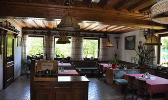A cozy restaurant with wooden furniture and large windows.  
Plants and tablecloths in soft colors create an inviting atmosphere.