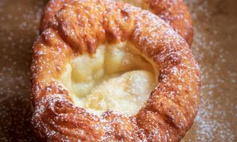 A few freshly baked, round pastries with a powdered sugar glaze. They have a golden-brown color and are filled.