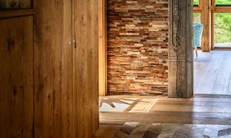 A stylish room with wood paneling and a patterned floor. Natural light pours in through a window, creating a cozy atmosphere.