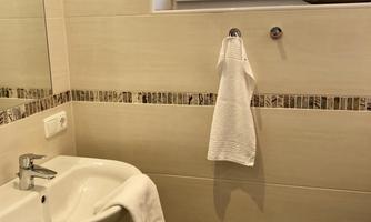 A modern bathroom with a small sink and a towel. The window is adorned with a decorative curtain.