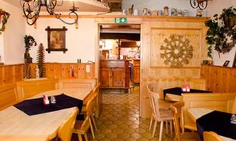 A cozy restaurant with wooden interiors and an inviting atmosphere. The tables are simply set, and the walls are adorned with decorative elements.