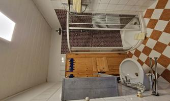 A bathroom with a shower, a sink, and a wooden shelf. The tiles are designed in a checkered pattern.