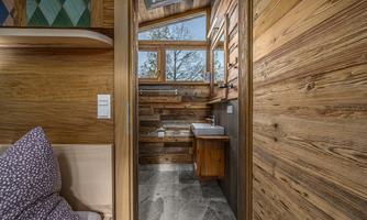 A cozy bathroom with wooden paneling and large windows. The natural light creates an inviting atmosphere.