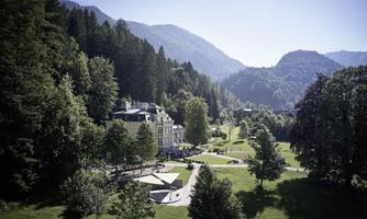A picturesque building surrounded by green trees and gentle hills. The landscape radiates tranquility and a connection to nature.