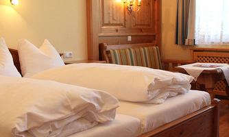 A cozy bedroom with two beds and large pillows. The room has warm colors and plenty of natural light.
