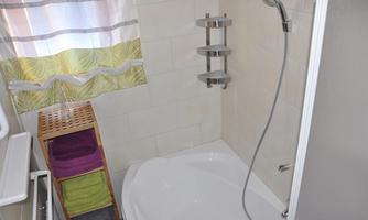 A modern bathroom with a shower and a bathtub. Towels in various colors are stacked on a shelf.