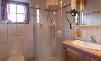 A modern bathroom with a shower, toilet, and wood paneling. It has bright tiles and a cozy atmosphere.