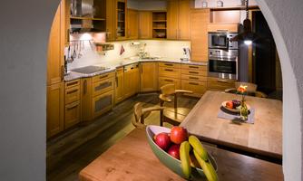 A modern kitchen with wooden cabinets and stylish appliances. A bowl of fresh fruit is on the table.