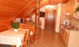A cozy kitchen with a wooden ceiling and a dining area. It features modern appliances and an inviting atmosphere.