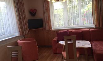 A cozy living space with a red sofa and a small table. Large windows provide plenty of daylight.