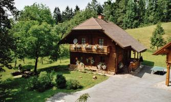 A picturesque wooden house with a large garden and many trees. The flowers on the balcony give the building a cozy atmosphere.