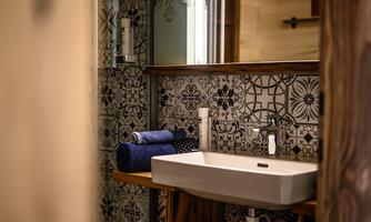 A modern bathroom with an elegant sink and decorative tiles. Towels in blue are ready for use.