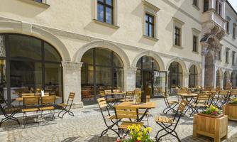 A cozy outdoor area with wooden tables and chairs. Colorful flower boxes create an inviting atmosphere.
